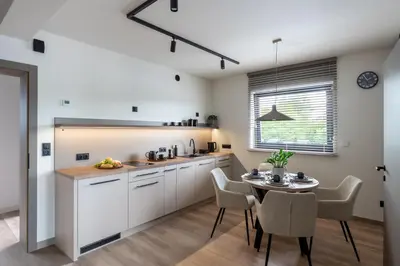 a kitchen with white cabinets and a table and chairs at Balice Apartamenty Premium - by Upstairs in Cholerzyn