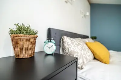 a alarm clock sitting on a table next to a bed at ShortStayPoland Siemieńskiego C5 in Kraków