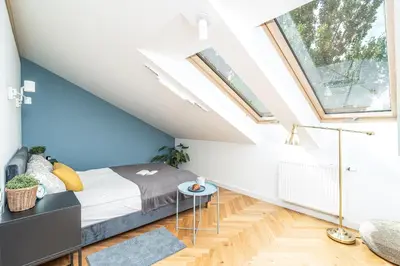 a attic bedroom with a bed and a window at ShortStayPoland Siemieńskiego C5 in Kraków
