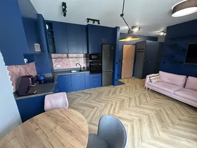 a living room with blue cabinets and a table and a couch at Pink Apartment Zabłocie in Kraków