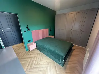 a bedroom with a bed and green walls and wooden floors at Pink Apartment Zabłocie in Kraków