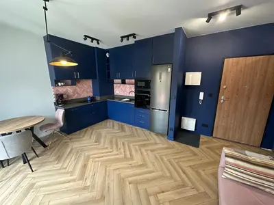 a kitchen with blue cabinets and a wooden floor at Pink Apartment Zabłocie in Kraków