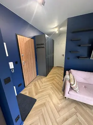 a living room with a couch and a blue wall at Pink Apartment Zabłocie in Kraków