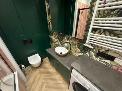a green bathroom with a toilet and a sink at Pink Apartment Zabłocie in Kraków