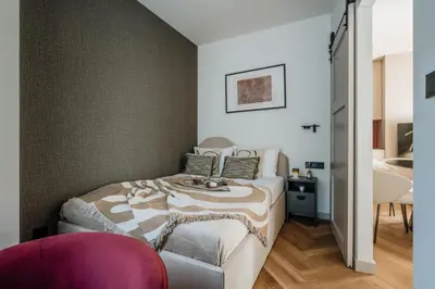 a bedroom with a bed and a pink chair at Electra Apartments by StayLab in Kraków