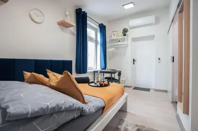 a bedroom with a bed with blue curtains and a window at Wiślane Apartamenty Kraków in Kraków
