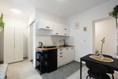 a kitchen with white cabinets and a black counter top at Wiślane Apartamenty Kraków in Kraków