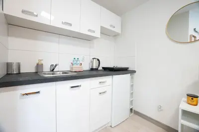 a white kitchen with a sink and a mirror at Wiślane Apartamenty Kraków in Kraków