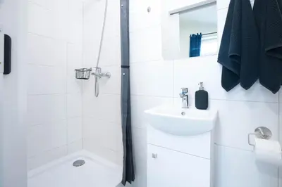 a white bathroom with a shower and a sink at Wiślane Apartamenty Kraków in Kraków