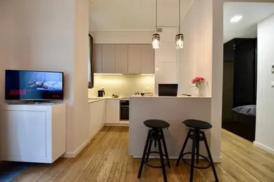 a kitchen with two bar stools and a tv at AWapartaments in Kraków