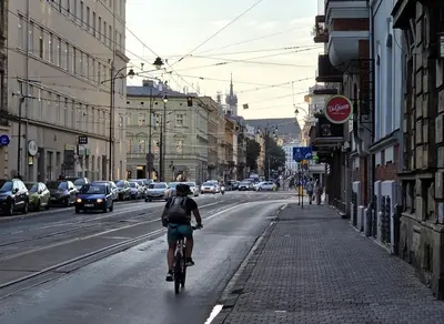 a person riding a bike down a city street at Kazimierz Art in Kraków