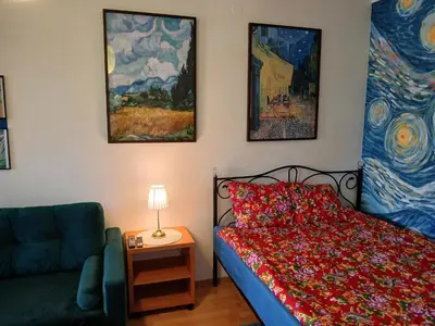 a bedroom with a bed and a couch and paintings at Meadow View 10 in Kraków