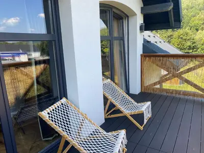 a pair of chairs sitting on a porch at Sielsko Anielsko Apartament in Zawoja