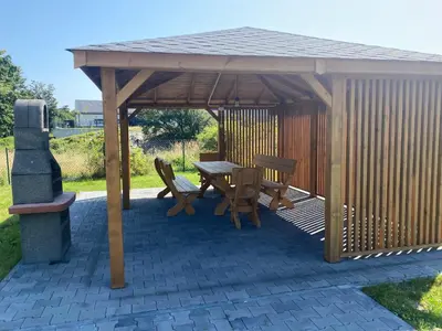 a wooden gazebo with a table and chairs under it at Sielsko Anielsko Apartament in Zawoja