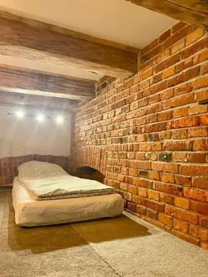 a brick wall with a bed in a room at Family Apartment with mezzanine in Kraków