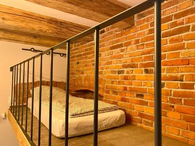 a bedroom with a brick wall and a bed in a room at Family Apartment with mezzanine in Kraków