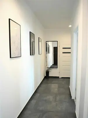 a hallway with white walls and pictures on the wall at Apartamenty Cisza Krakow in Kraków
