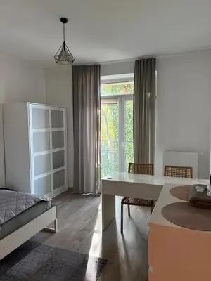 a bedroom with a bed and a desk and a window at Apartamenty Cisza Krakow in Kraków