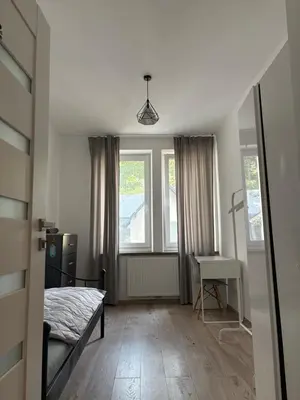 a bedroom with a bed and a desk and windows at Apartamenty Cisza Krakow in Kraków