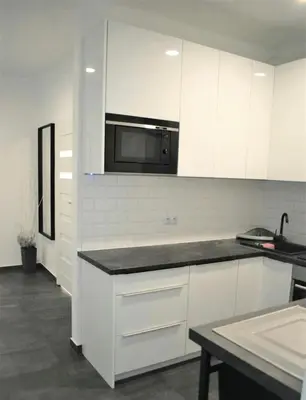 a kitchen with white cabinets and a microwave at Apartamenty Cisza Krakow in Kraków
