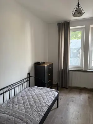 a bedroom with a bed and a dresser and a window at Apartamenty Cisza Krakow in Kraków