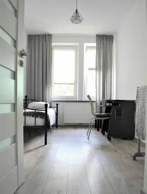 a bedroom with a desk and a bed and a window at Apartamenty Cisza Krakow in Kraków