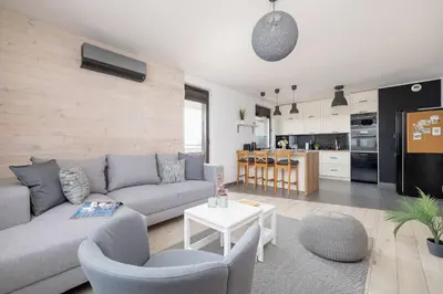 a living room with a couch and chairs and a kitchen at 6th Floor Apartment in Cracow by Noclegi Renters in Kraków