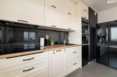 a kitchen with white cabinets and a black refrigerator at 6th Floor Apartment in Cracow by Noclegi Renters in Kraków
