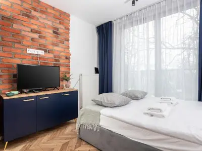 a bedroom with a bed with a tv on a brick wall at Nowoczesny apartament nad Wisłą in Kraków