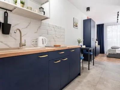a kitchen with blue cabinets and a sink and a bed at Nowoczesny apartament nad Wisłą in Kraków