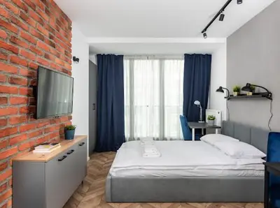 a bedroom with a bed and a brick wall at Nowoczesny apartament nad Wisłą II in Kraków