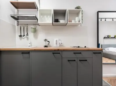 a kitchen with white cabinets and a wooden counter top at Nowoczesny apartament nad Wisłą II in Kraków