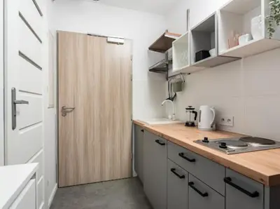a small white kitchen with a wooden counter top at Nowoczesny apartament nad Wisłą II in Kraków