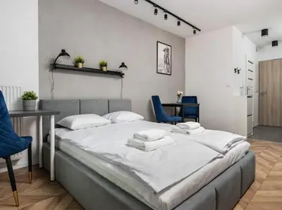 a large bed in a room with two blue chairs at Nowoczesny apartament nad Wisłą II in Kraków