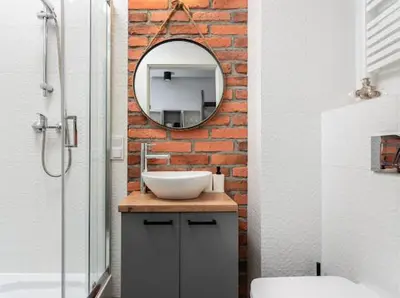 a bathroom with a sink and a mirror on a brick wall at Nowoczesny apartament nad Wisłą II in Kraków