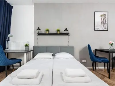 a bedroom with a bed and two blue chairs at Nowoczesny apartament nad Wisłą II in Kraków