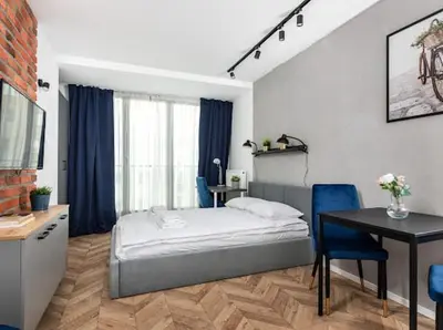 a bedroom with a bed and a desk and a table at Nowoczesny apartament nad Wisłą II in Kraków
