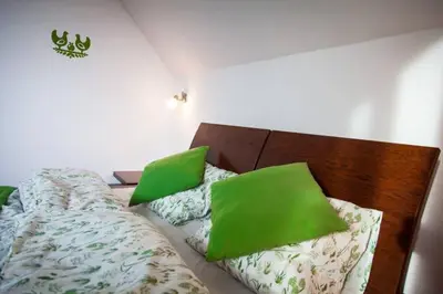 a bedroom with a bed with green pillows on it at Garden Apartament Kurnik in Stróża