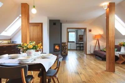 a dining room and living room with a table and chairs at Garden Apartament Kurnik in Stróża