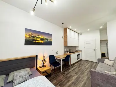 a living room with a couch and a table and a kitchen at Mariacki apartment in Kraków