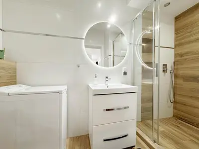a white bathroom with a sink and a shower at Mariacki apartment in Kraków