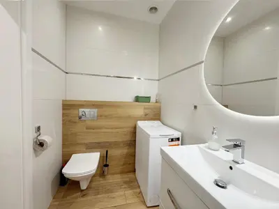 a white bathroom with a toilet and a sink at Mariacki apartment in Kraków