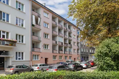 a row of cars parked in front of a pink building at Nowowiejska Cosy Studio for 6 people in Cracow by Noclegi Renters in Kraków