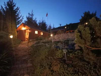 a wooden cabin with lights in a garden at night at Dom w Chomranicach- Jacuzzi, domek grillowy in Chomranice