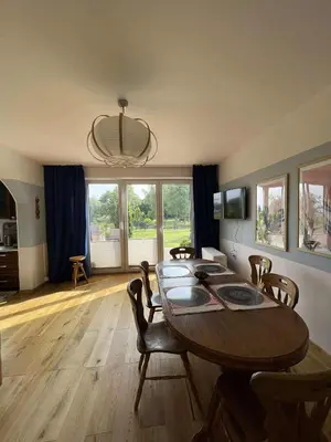 a dining room with a wooden table and chairs at Apartamenty TUTERRA I in Zabagnie