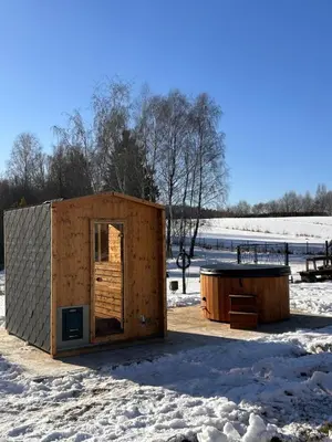 a wooden cabin with a tub in the snow at Apartamenty TUTERRA I in Zabagnie