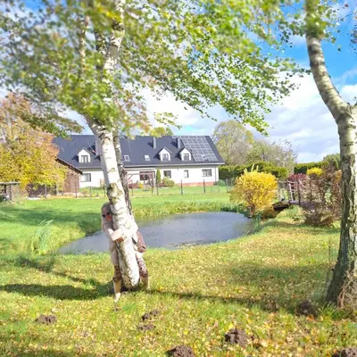 a young child is climbing a tree near a pond at Apartamenty TUTERRA I in Zabagnie