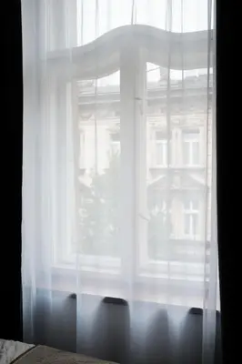 a window with white curtains in front of a building at Vintage Soul Kazimierz Old Town in Kraków