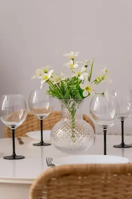 a vase with flowers in it on a table with wine glasses at Dietla Family Apartment in Kraków City Center by Noclegi Renters in Kraków