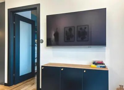 a room with a television on a wall with a cabinet at Bakelit Studio - Design hideaway - Calm, quality & location in Kraków